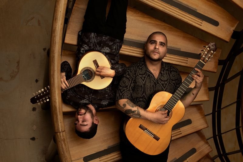 Vista cenital de Brayan Ruiz con la bandola y David Valencia con la guitarra en una escalera de caracol